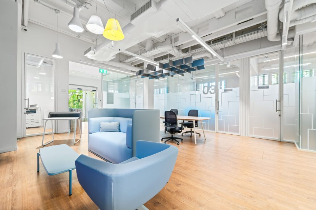 Interno di uno spazio di co-working moderno con arredi luminosi e stanze vetrate.